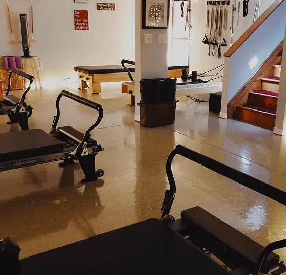 The ABS Pilates studio floor after hours, Reformers in the foreground and a Tower against the far wall