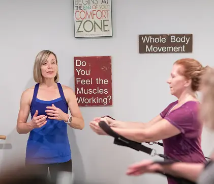 Amanda Smith talking a class through an exercise, hands on her ribs to demonstrate breathing